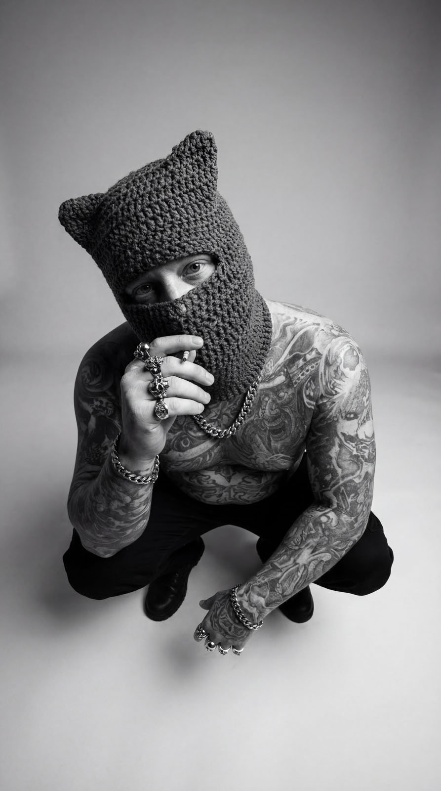 Tattooed figure in a knit balaclava crouching low